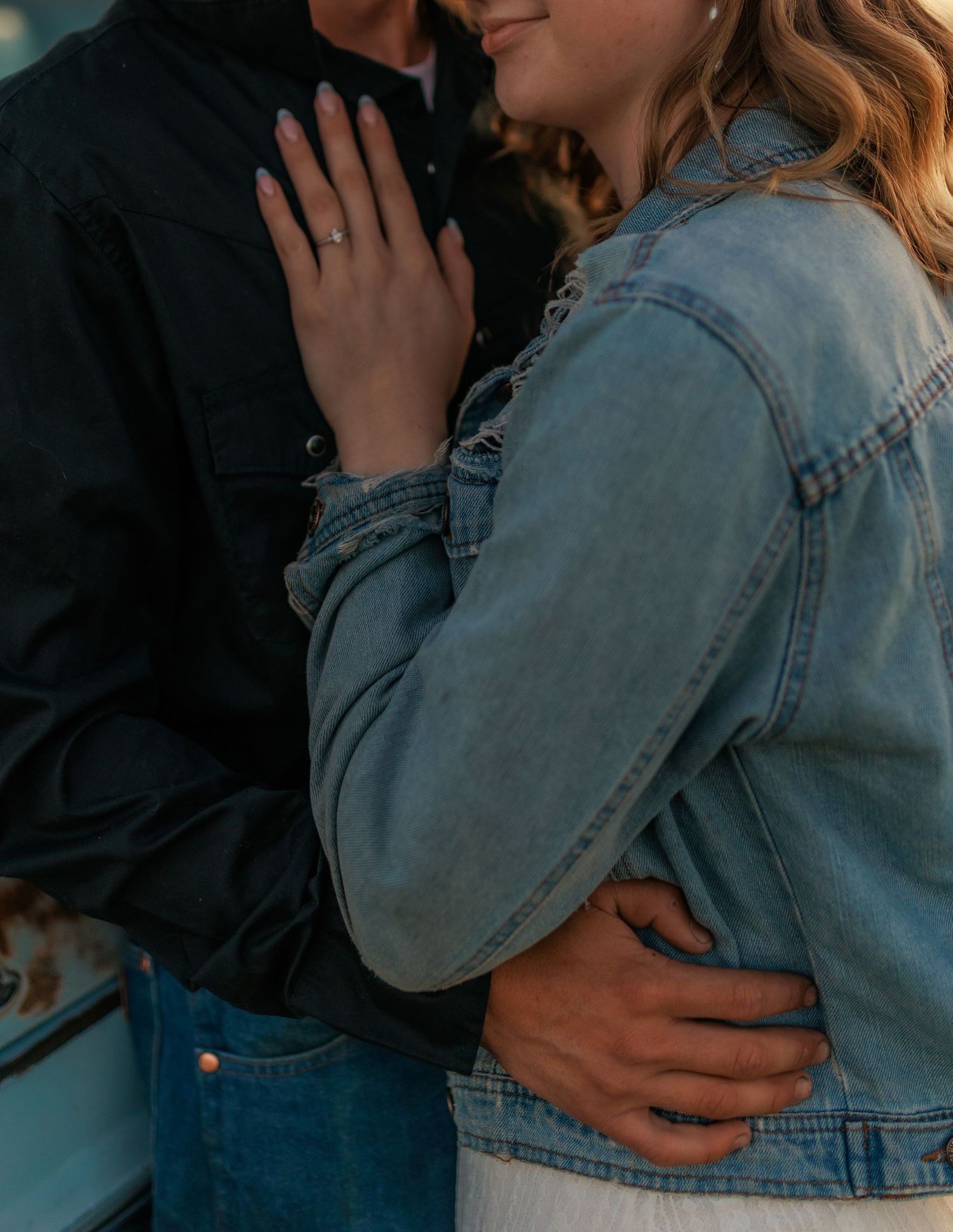 Close-up of an affectionate embrace with denim jacket details.