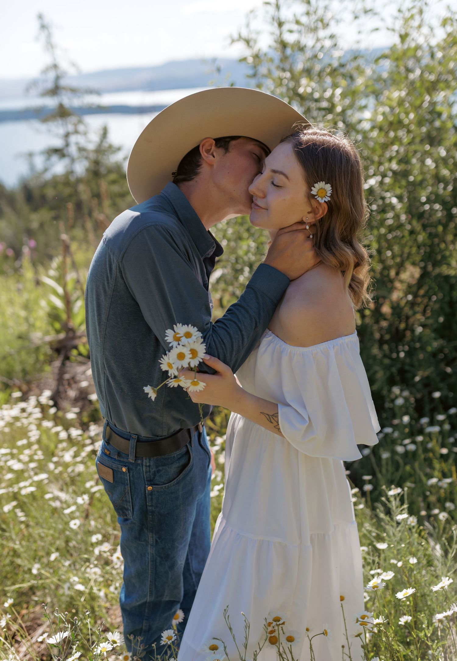 Romantic couple embracing in a wildflower meadow with mountain views.