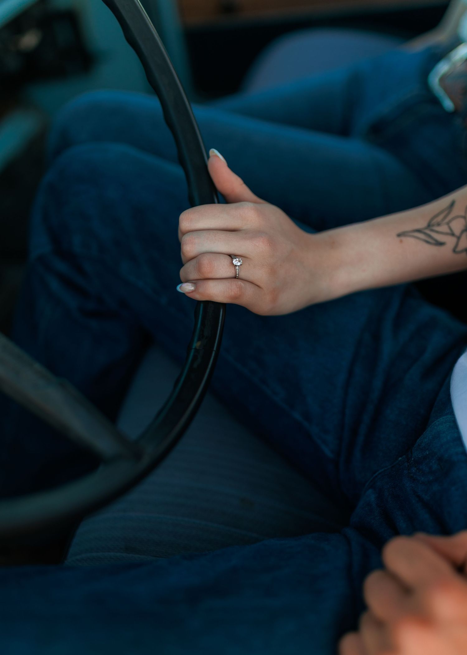 Hand with engagement ring grips steering wheel of classic truck interior.