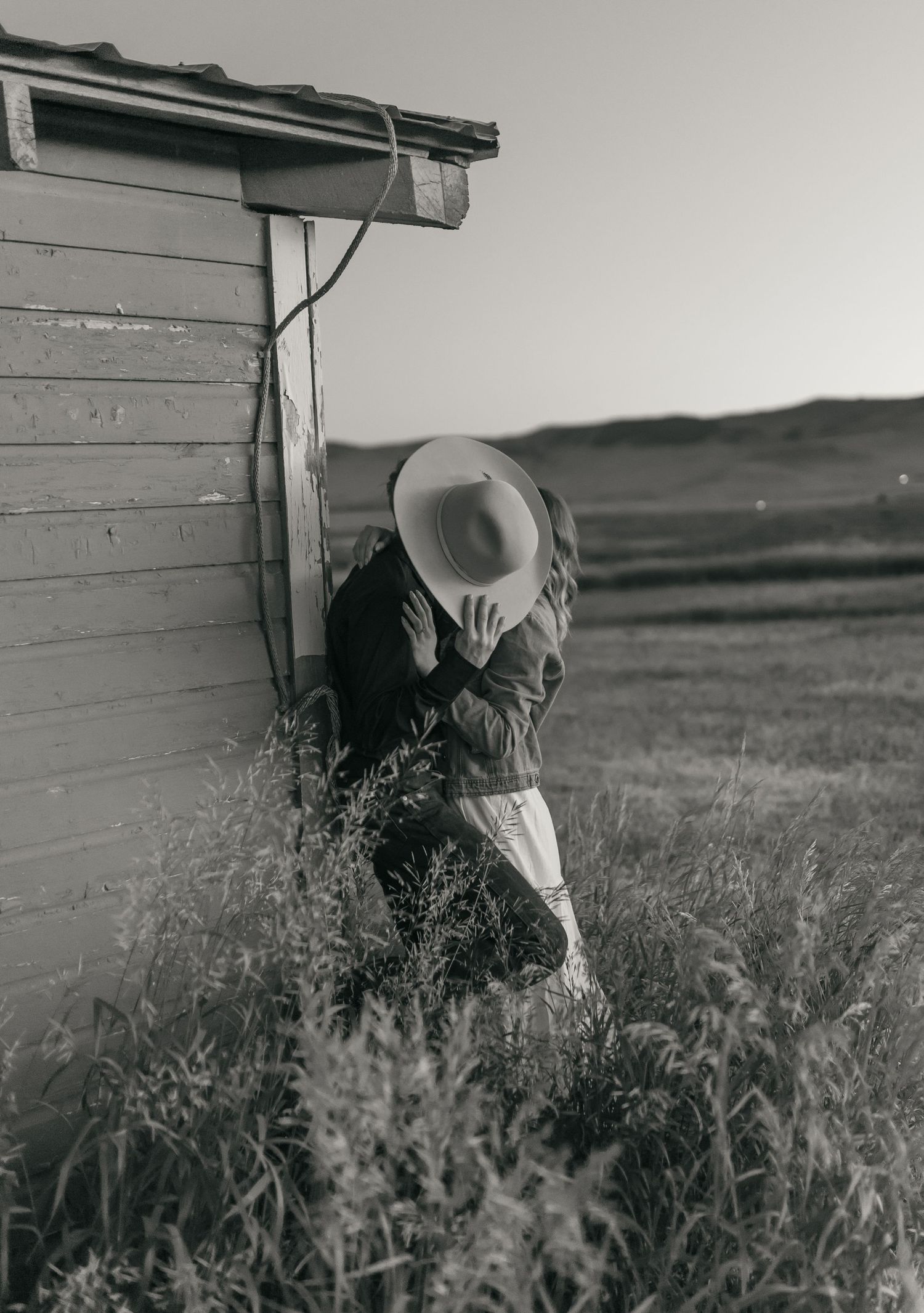 A black and white series showing romantic moments beside a rural building.