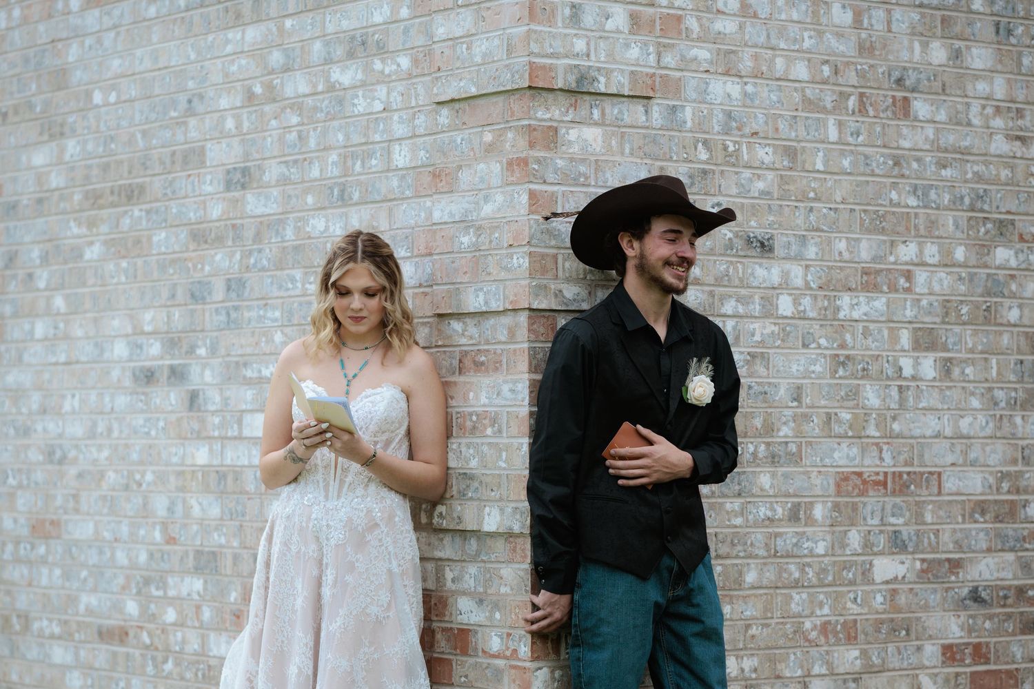 Bride and groom in black cowboy hat at rustic outdoor Montana venue while they do their first touch and emotional private vows.