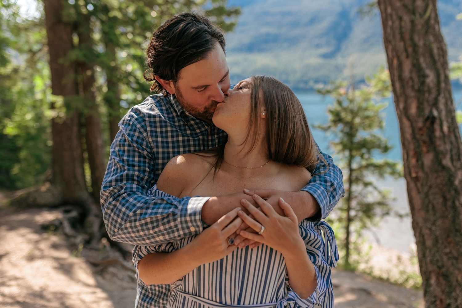 Intimate embrace captured on a forest trail overlooking a scenic mountain lake.