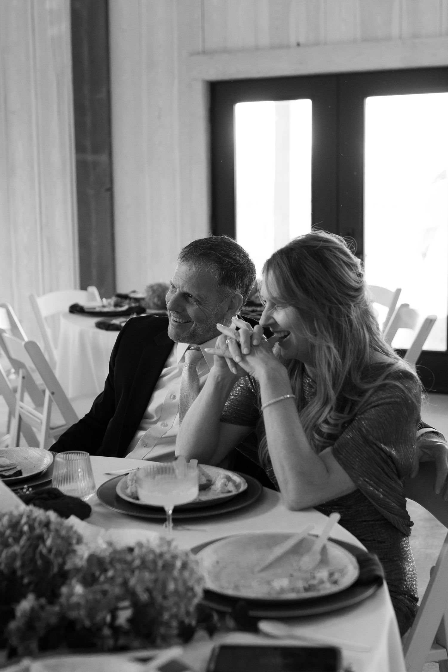 black and white photo of parents of the groom getting emotional while listening to a wedding speech at Montana wedding
