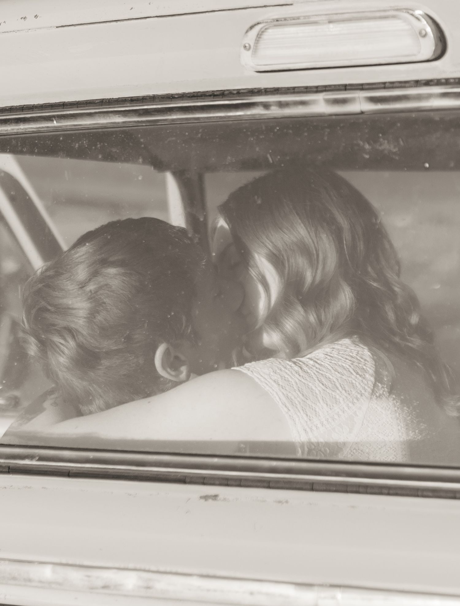 Vintage black and white photo showing silhouettes through car windows.