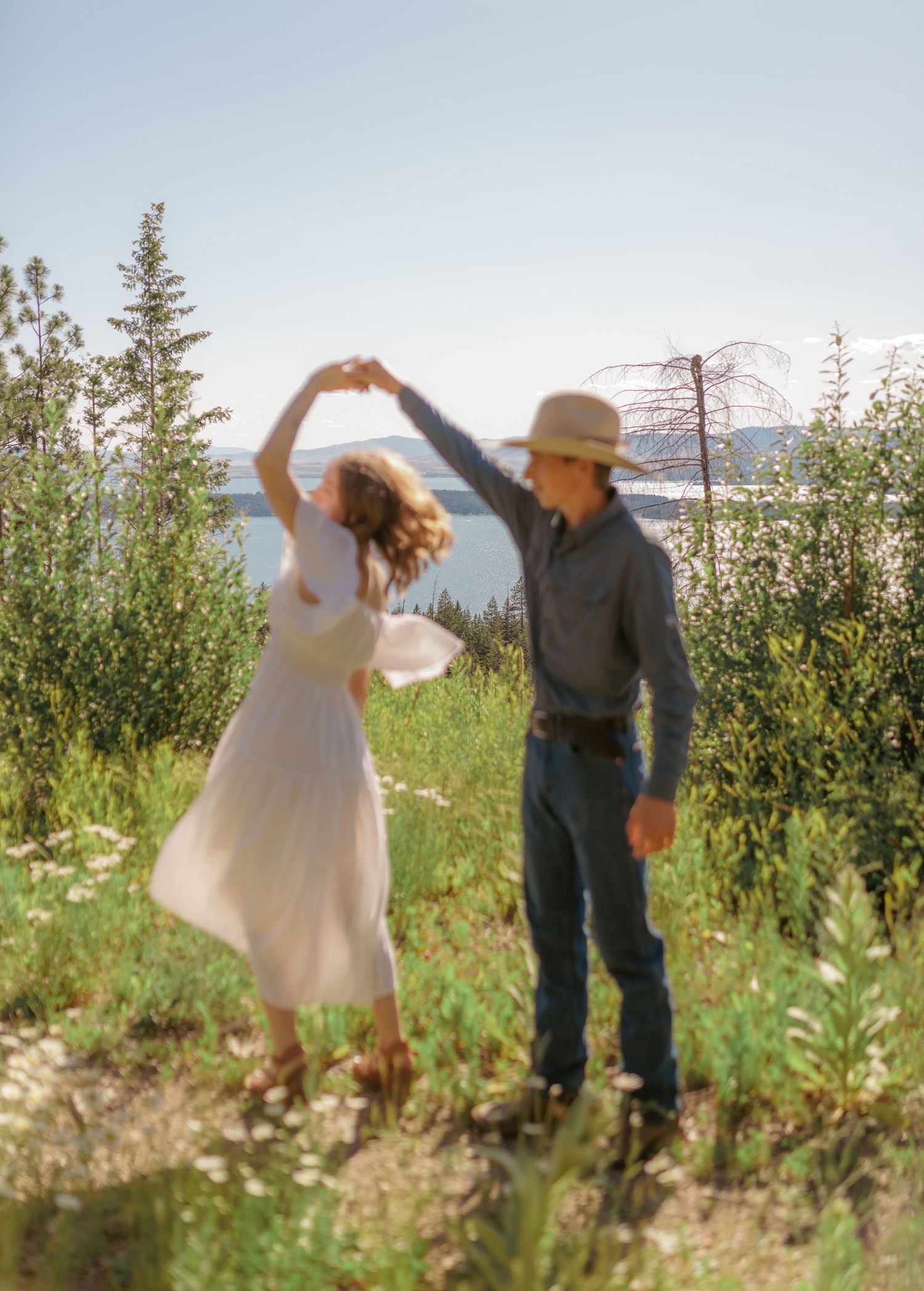 Dancing and twirling in a sunlit meadow with mountains in the background.