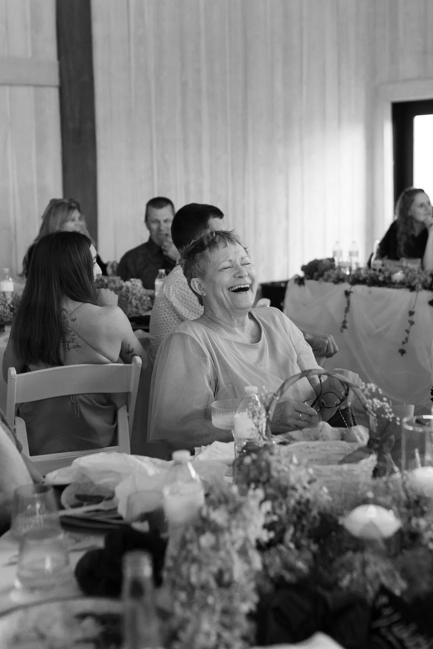 black and white photo of bride's grandma laughing during wedding speech at Montana wedding