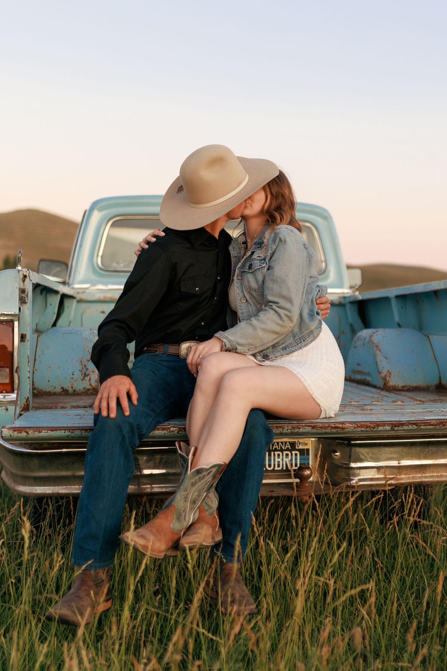 Romantic moment captured on an old blue pickup truck bed in a meadow at dusk.