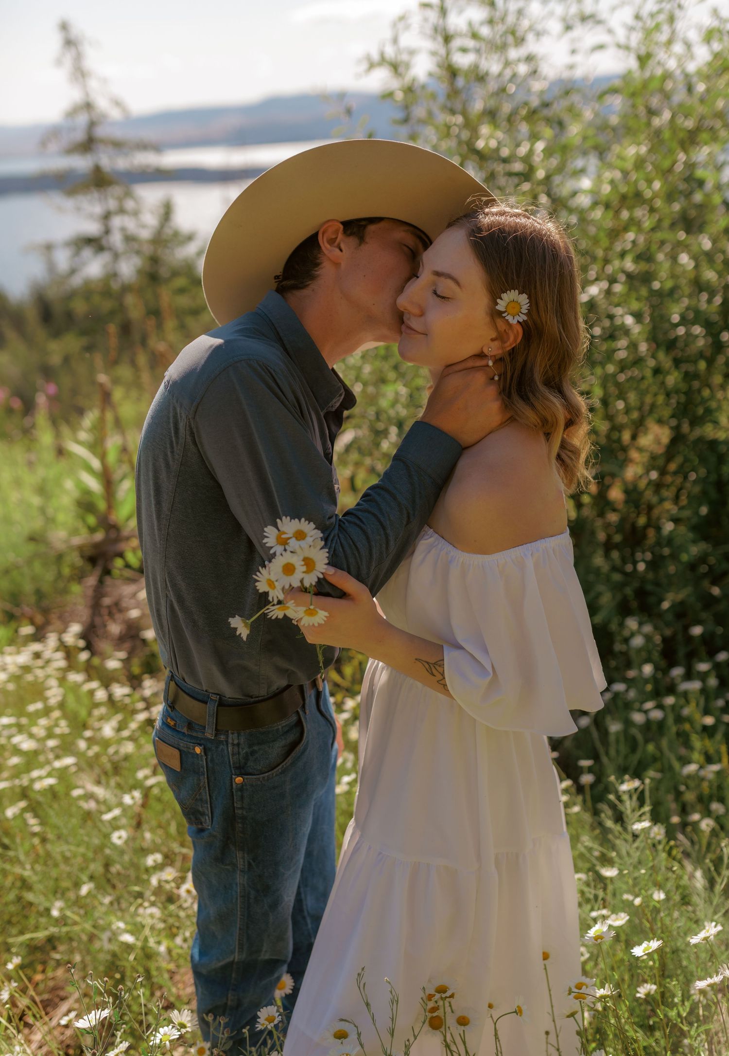 A romantic couple shares tender moments in a wildflower meadow with mountains in the background.