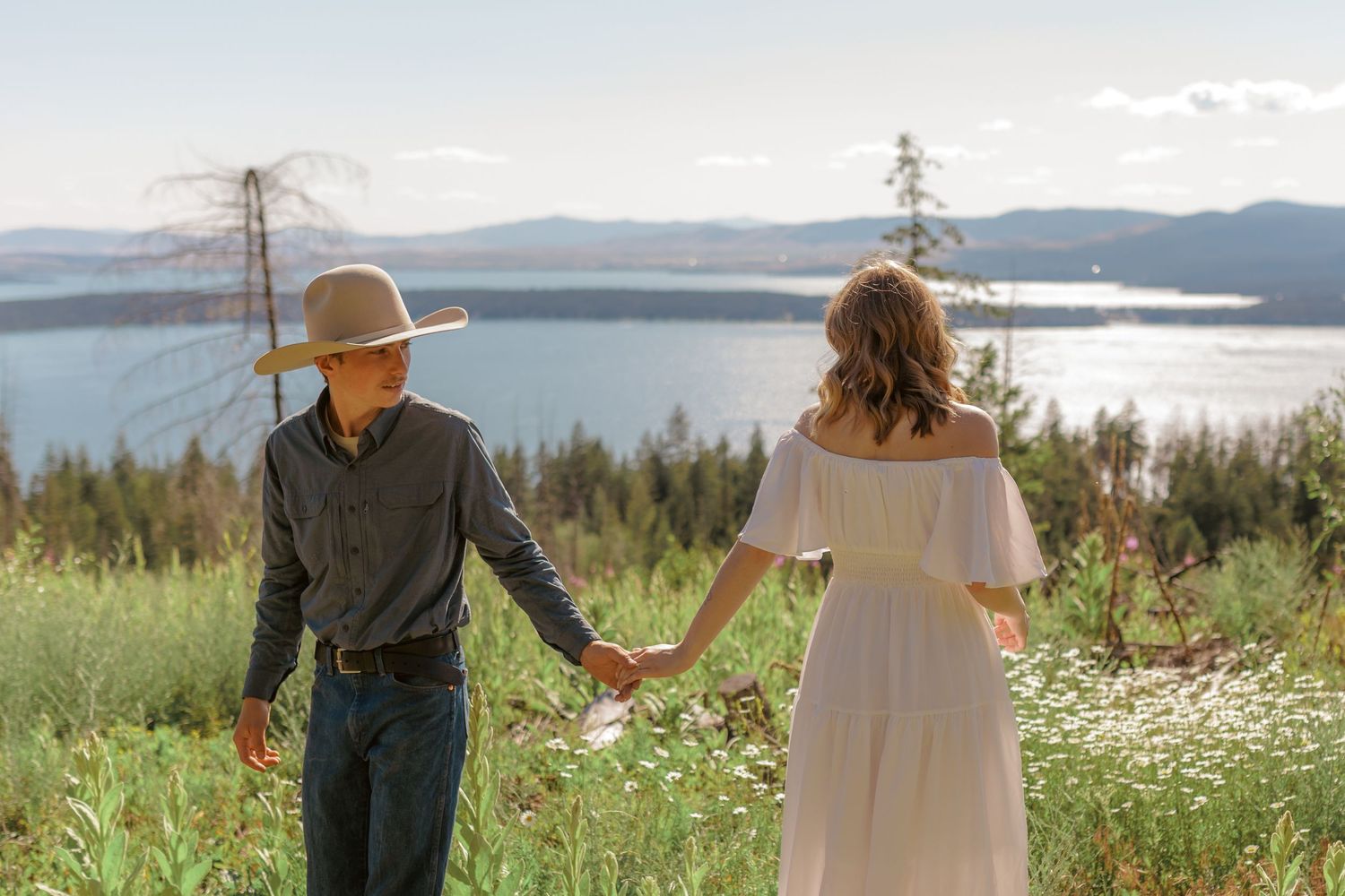 Romantic scene in a wildflower field with mountains and water in the distance.