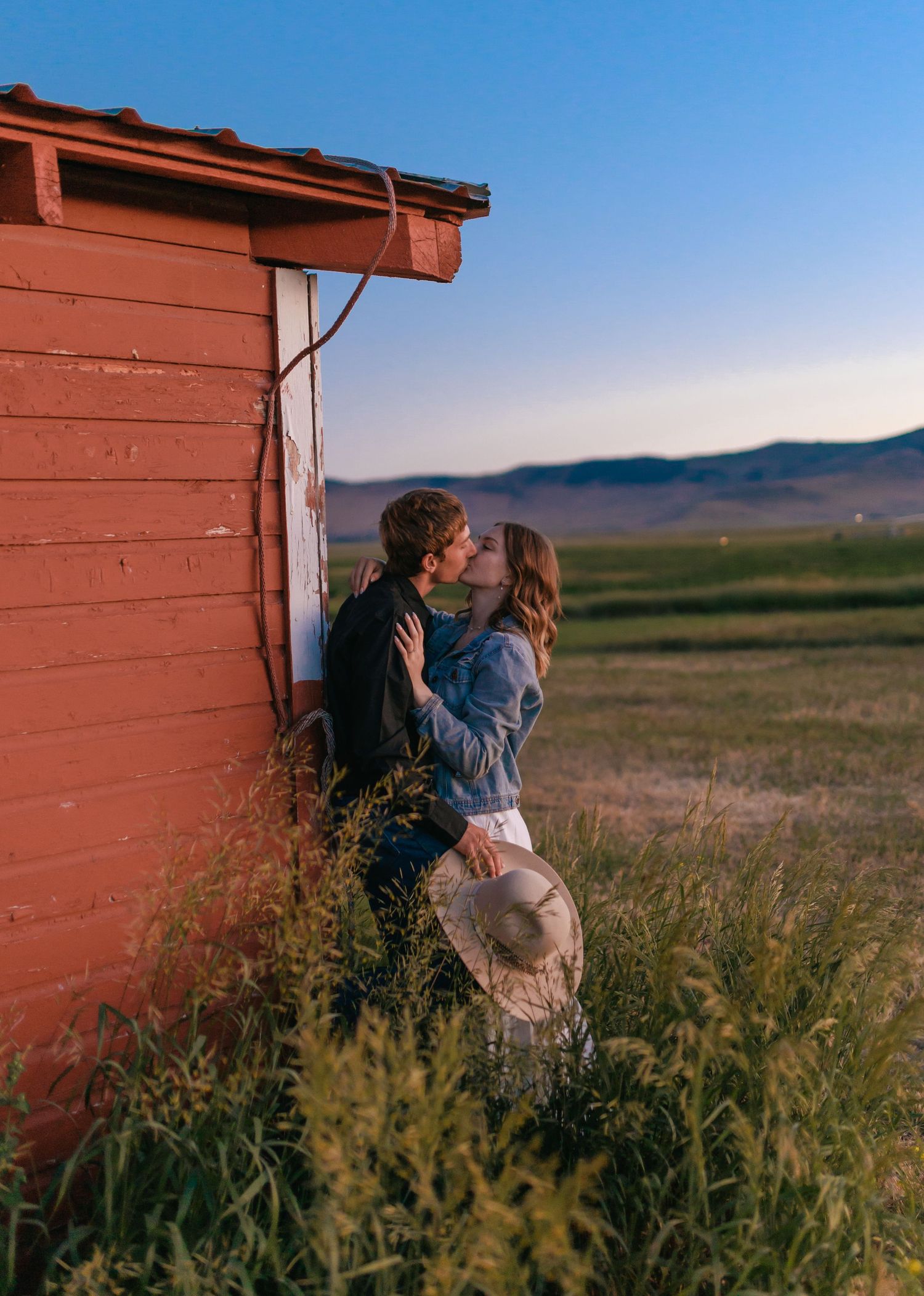 Romantic sequence by red barn in prairie landscape at dusk.