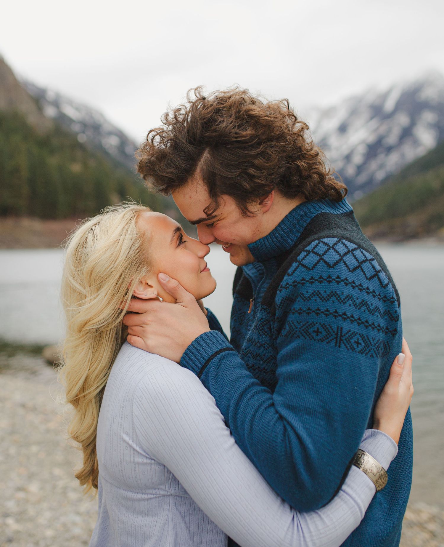 Intimate portrait of couple sharing sweet moment by mountain lake.