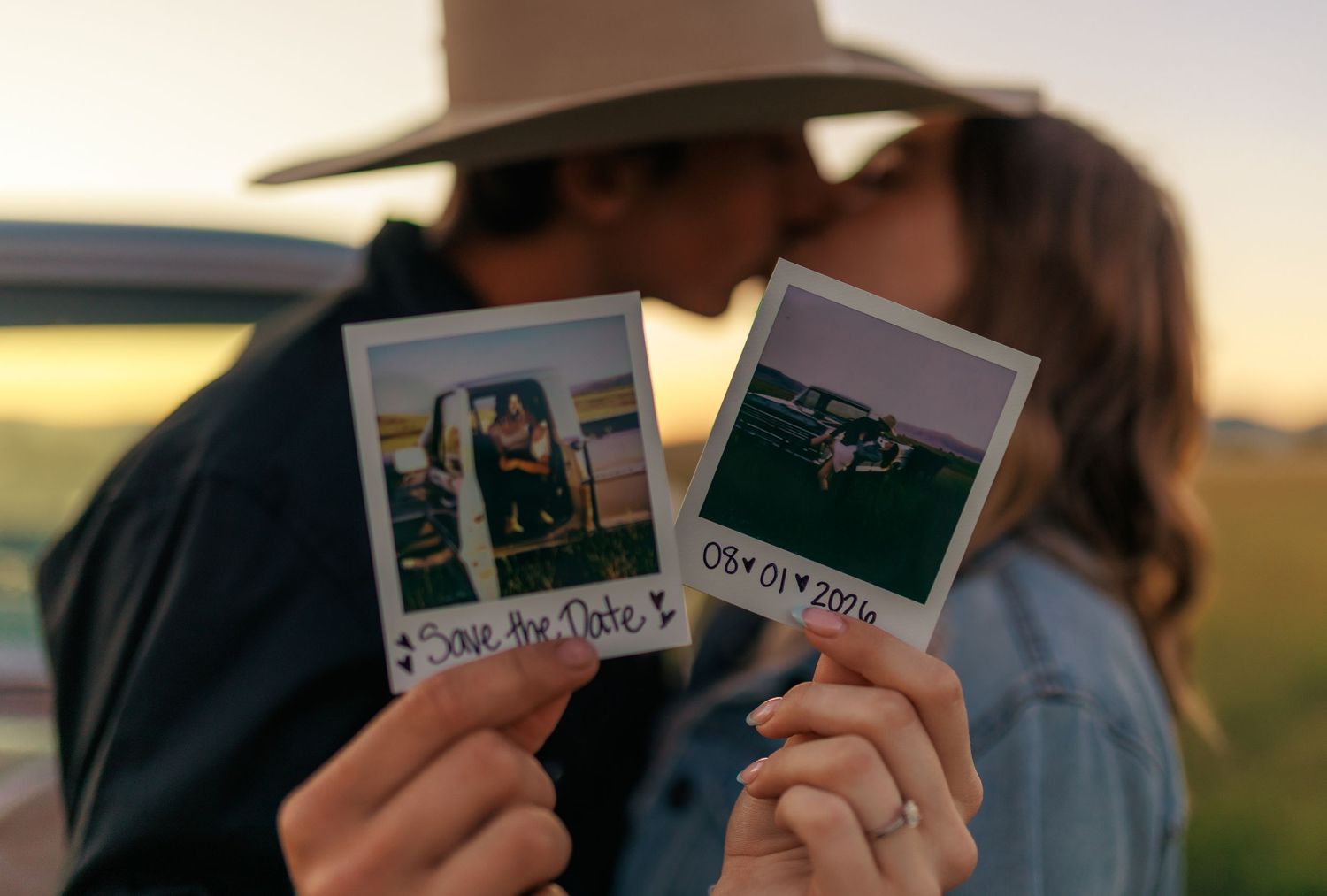 Couple sharing Polaroid photos during sunset in a rural setting.