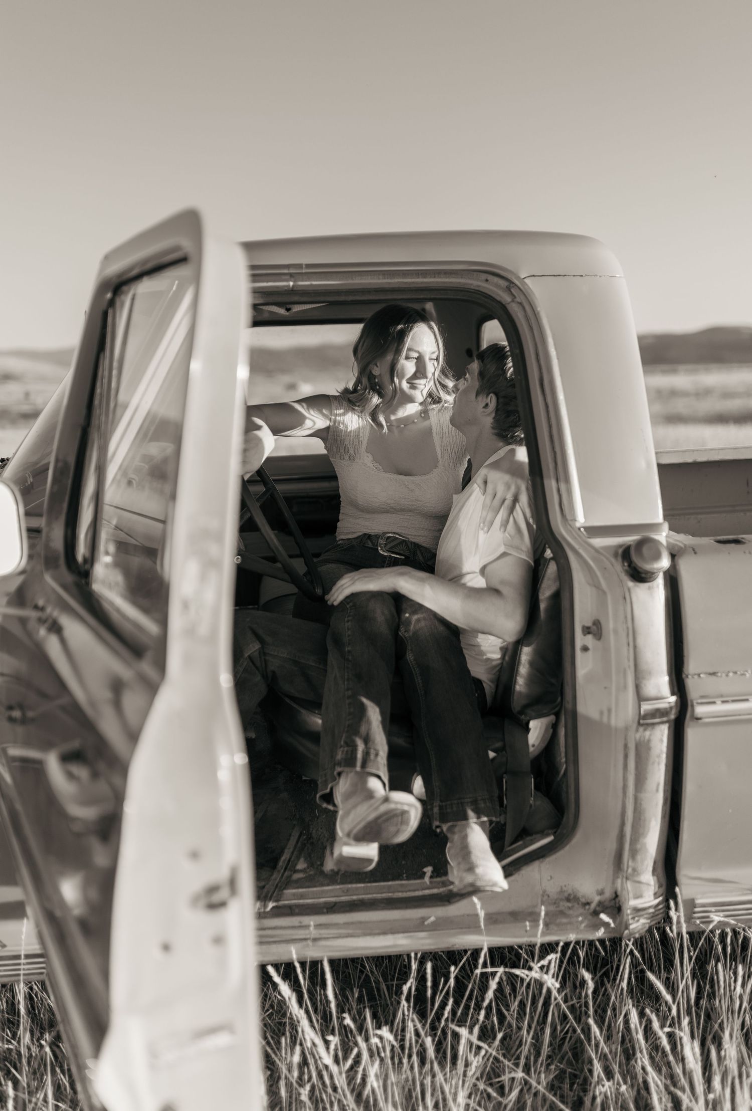 Black and white photograph inside a vintage car with soft interior lighting.
