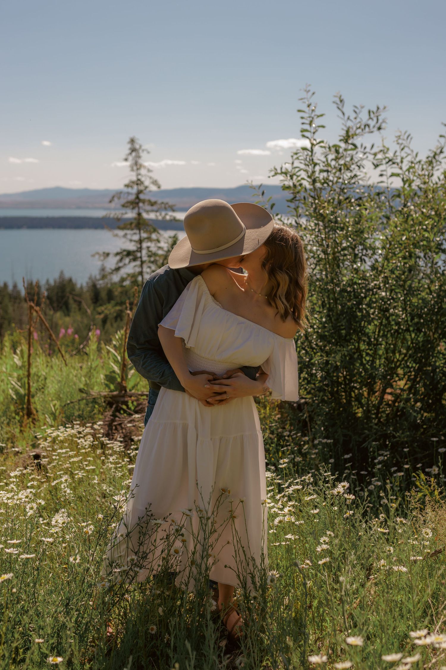Couple shares an embrace while standing in a field of mountain wildflowers.