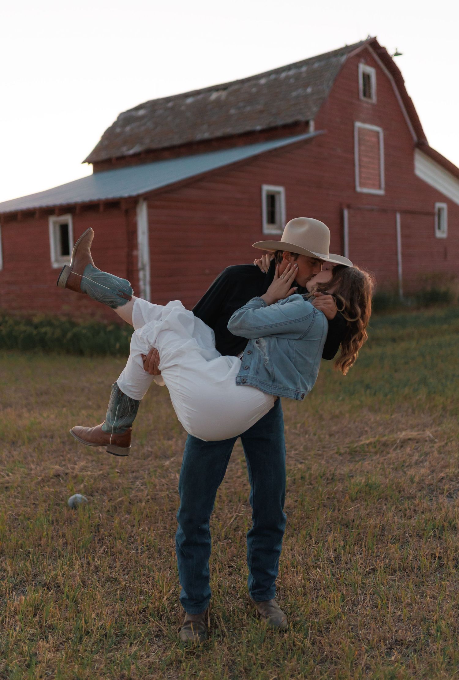 Playful dance sequence in front of weathered red barn at sunset.