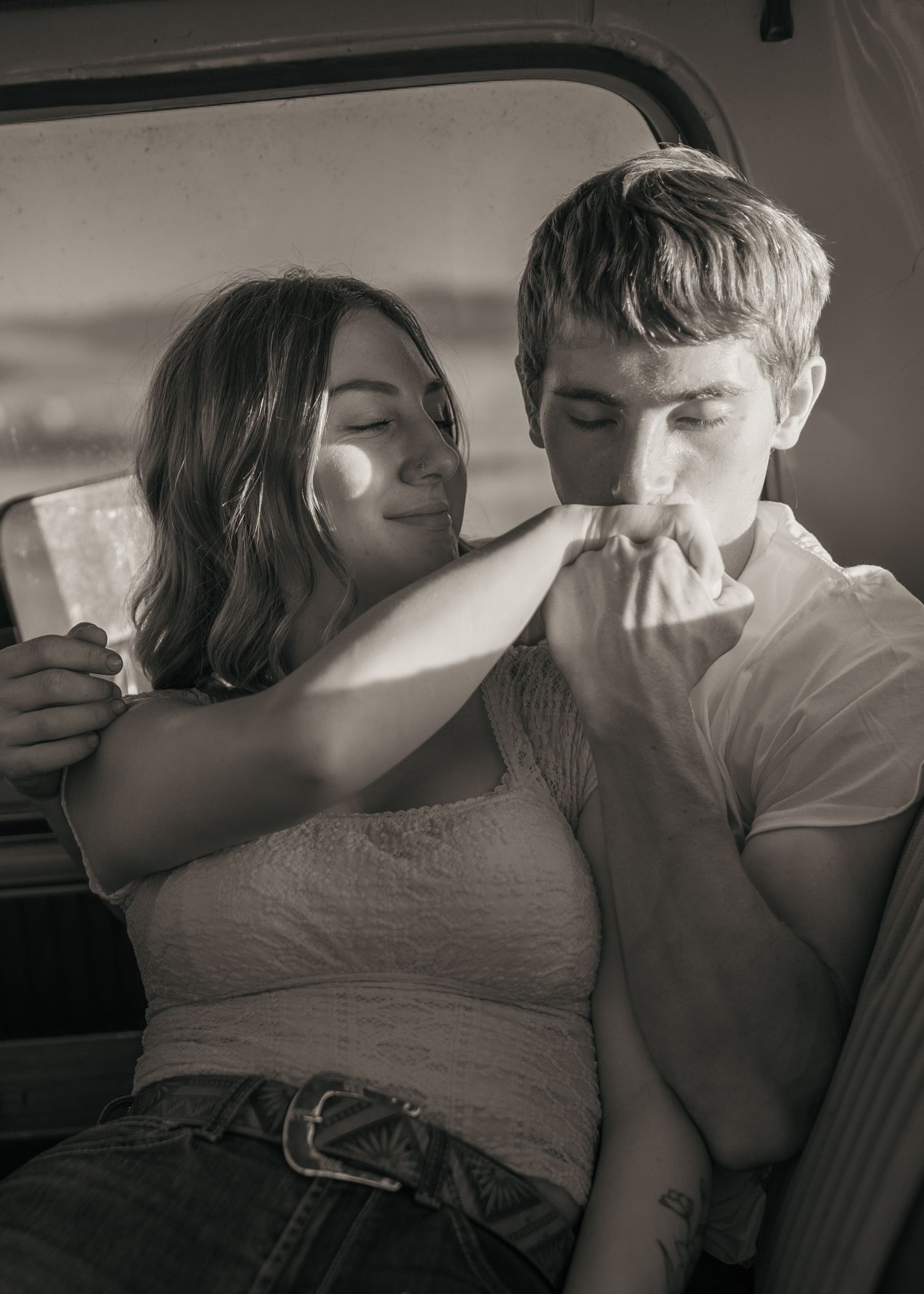 Intimate black and white moment captured inside a classic car interior.
