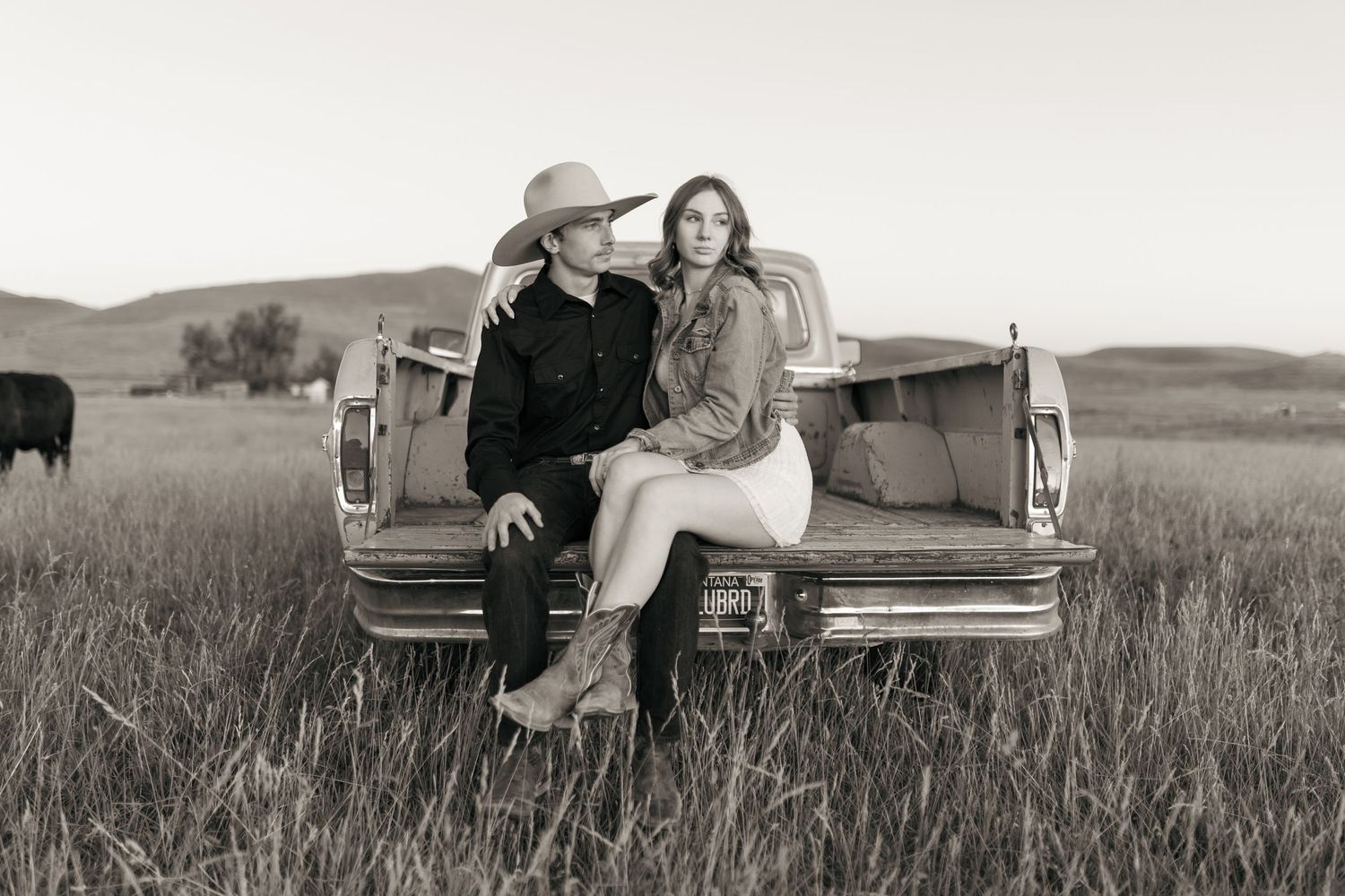 A classic pickup truck provides backdrop for romantic photos in a serene field setting.