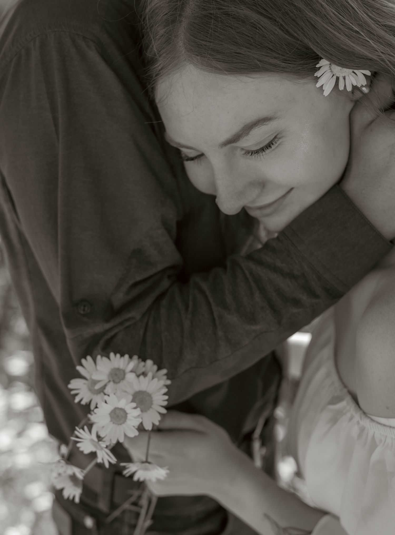 An artistic black and white closeup of a romantic moment with daisies.