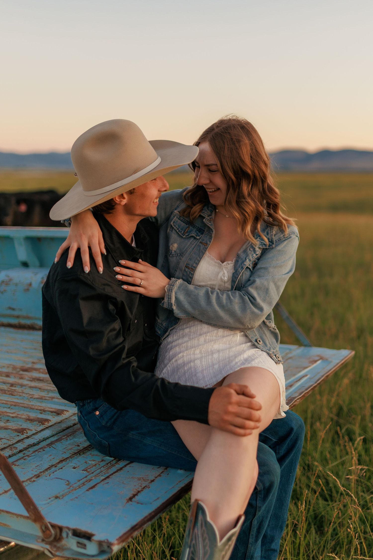 Intimate couple moment on back of classic pickup truck during golden hour.