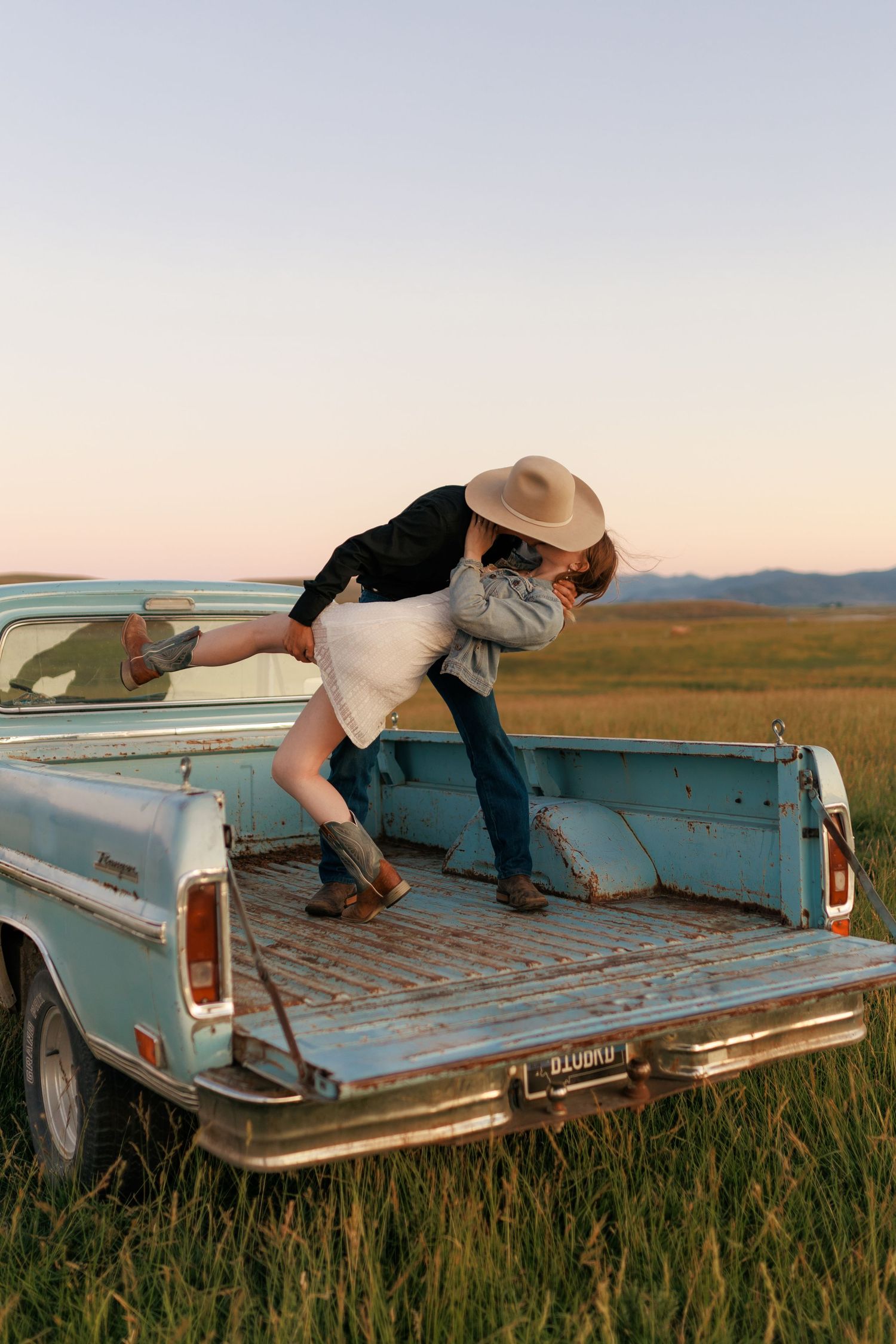 Dance-like poses on the bed of a classic blue pickup truck in a golden field.