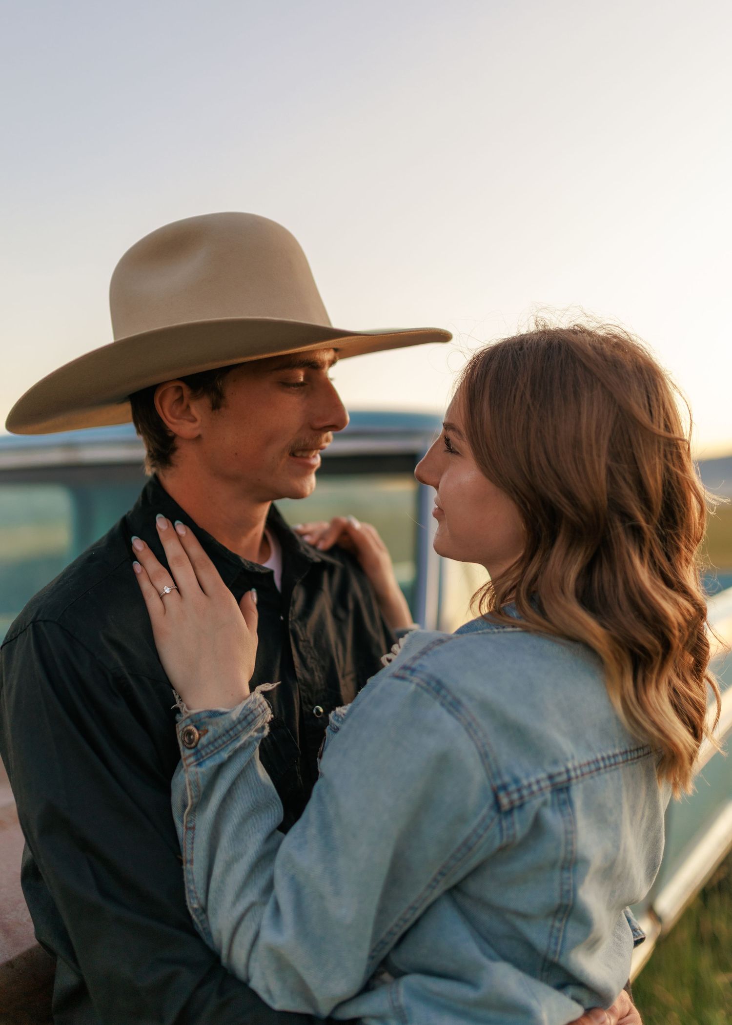 Romantic couple in western wear sharing intimate moments by their classic car.