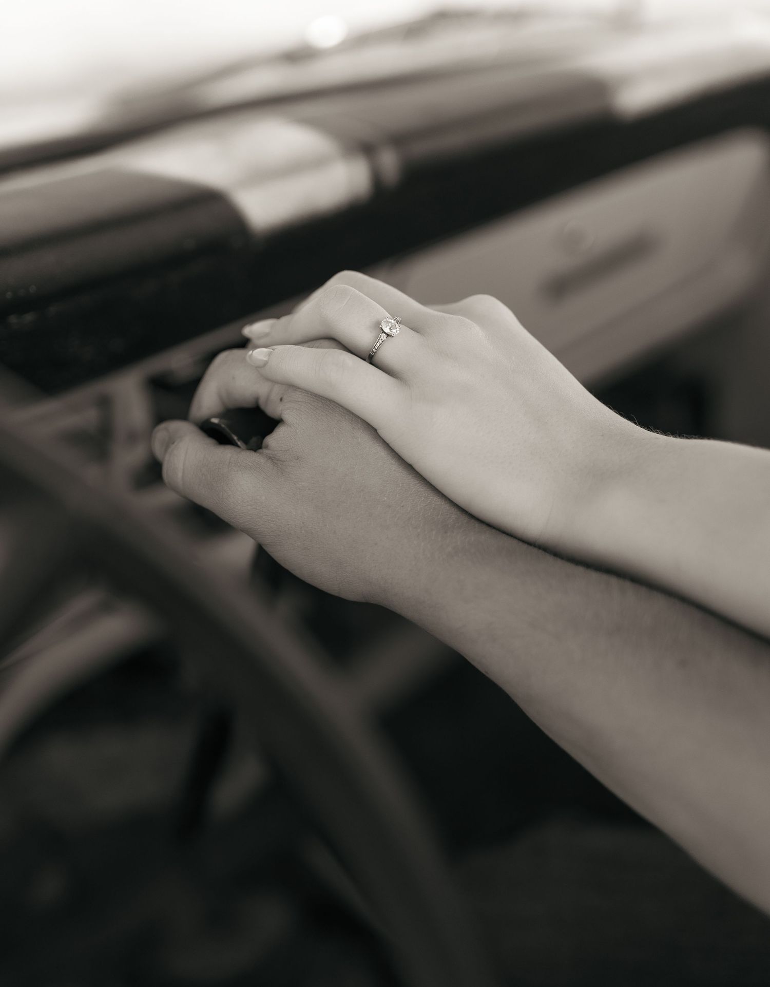 Close-up black and white photo of hands against a blurred dark background.