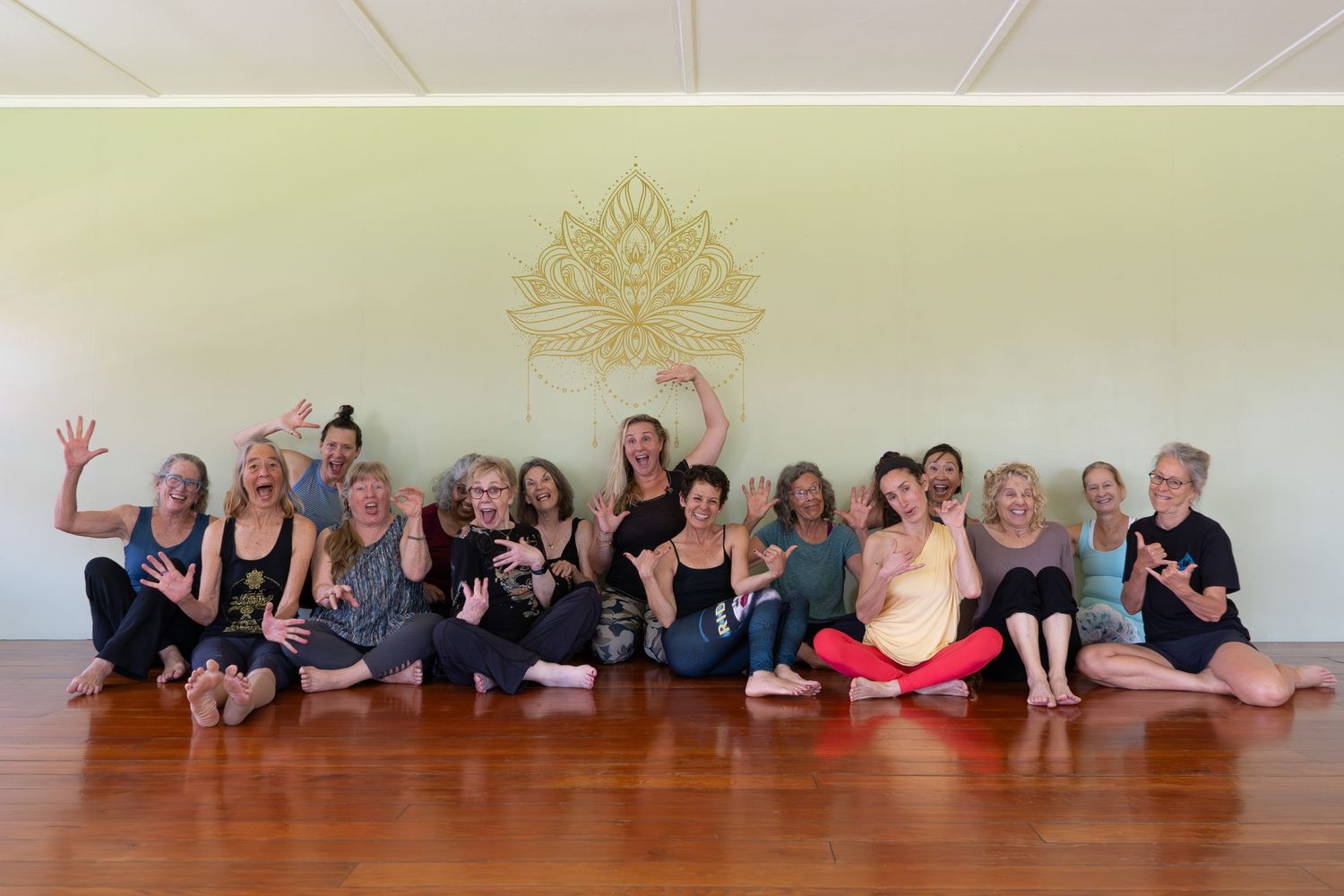 Group of dancers lying on a wooden floor in a dance studio during a choreographed performance piece.