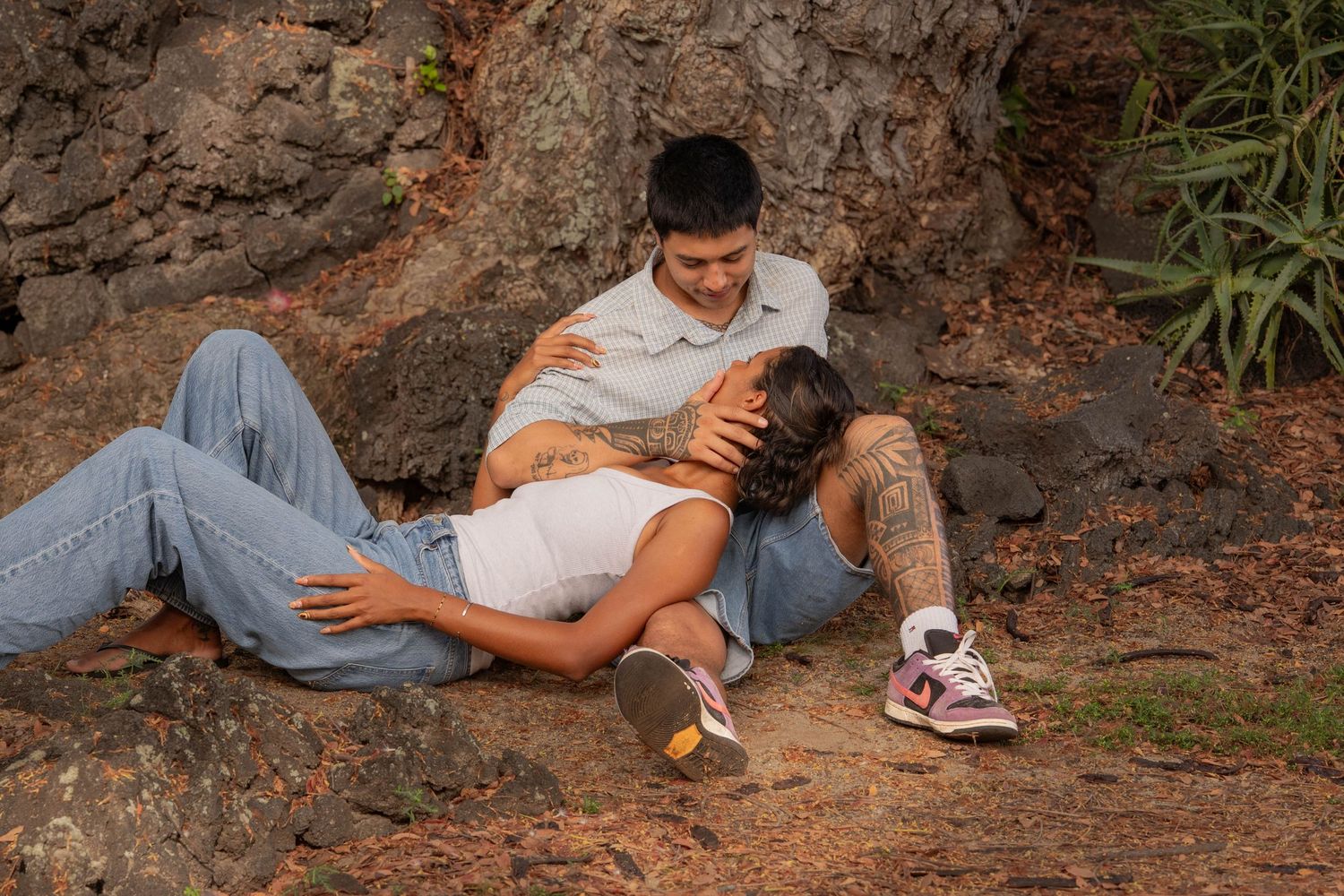 Couple relaxing together against a rocky surface outdoors, woman resting her head on man's lap.