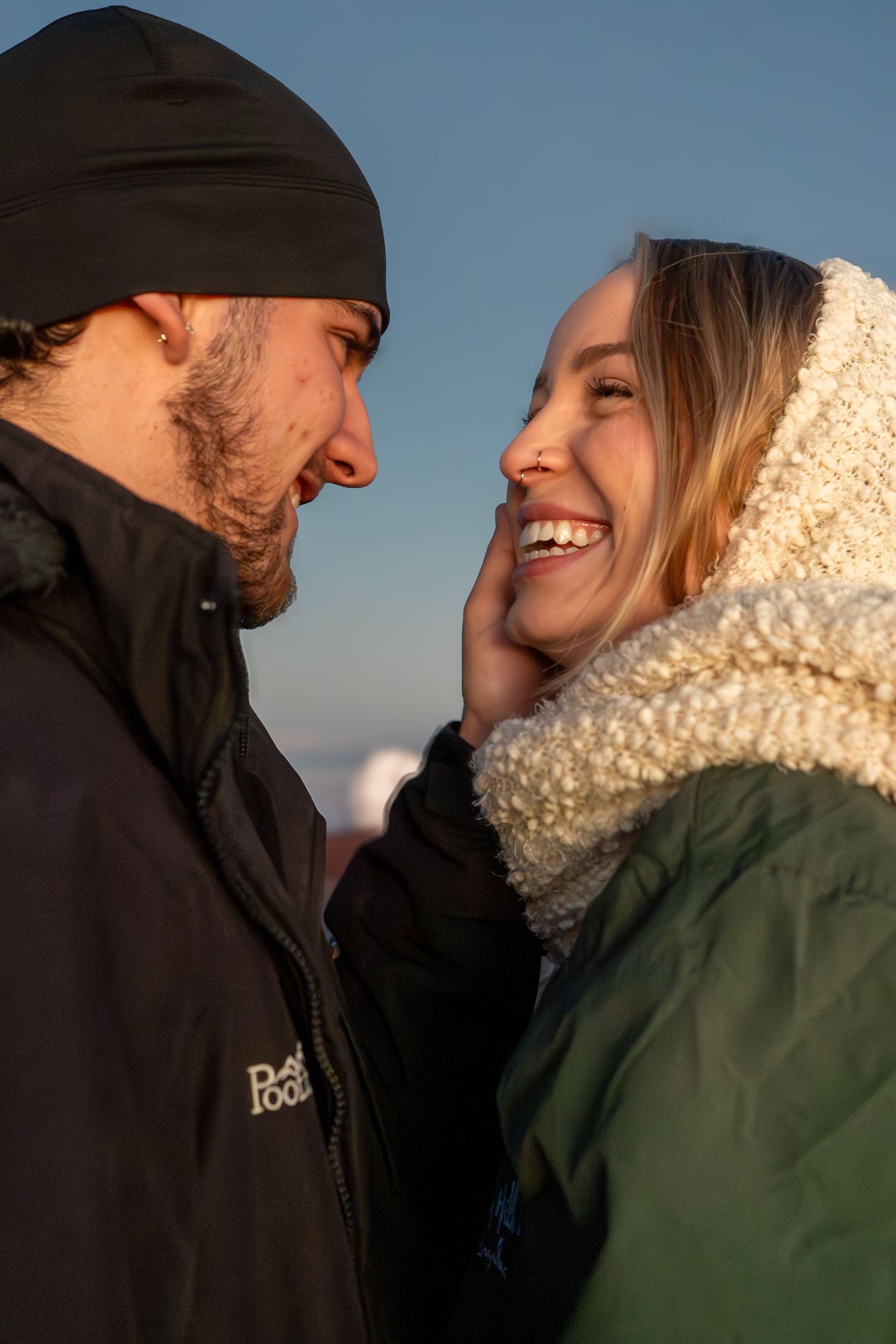 A couple shares intimate laughter and tender moments in a series of candid outdoor photos against a blue sky background.