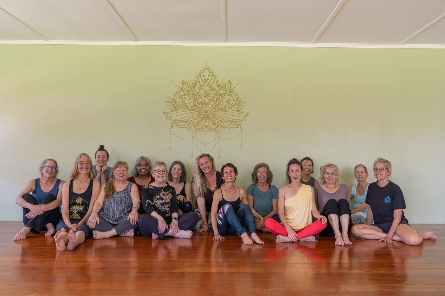 A group of people lying on the floor in a dance studio doing stretching exercises together.