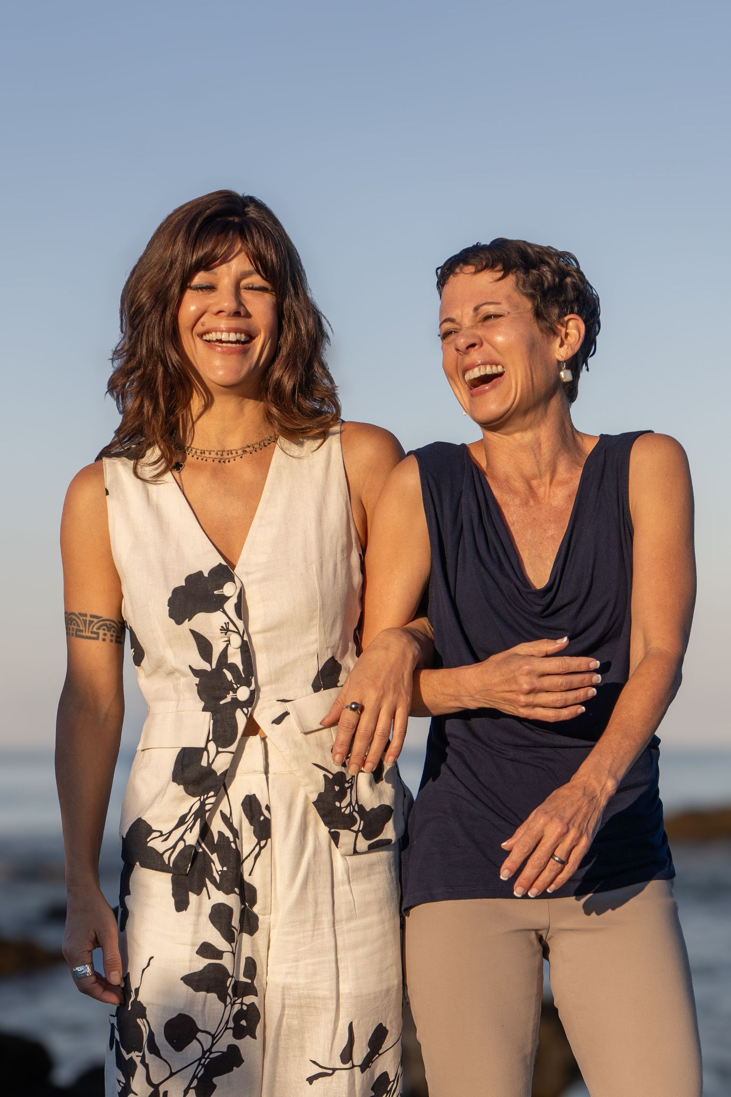 Two friends share a joyful moment of laughter together on a sunny day at the beach.