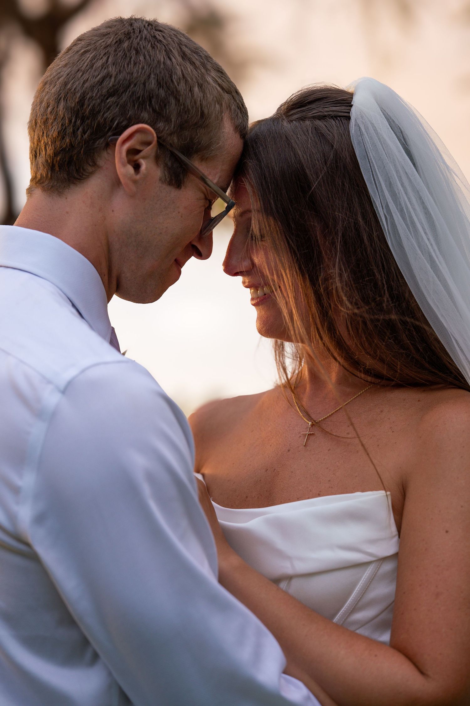 Bride and groom in intimate forehead touch moment during romantic outdoor wedding portrait.