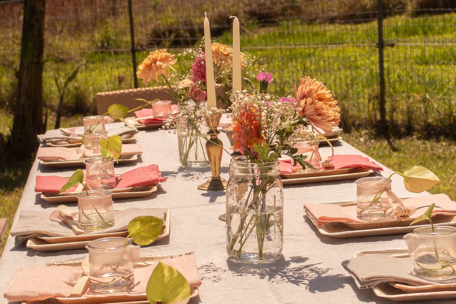 Elegant table setting with pink flowers and candles for outdoor dining.