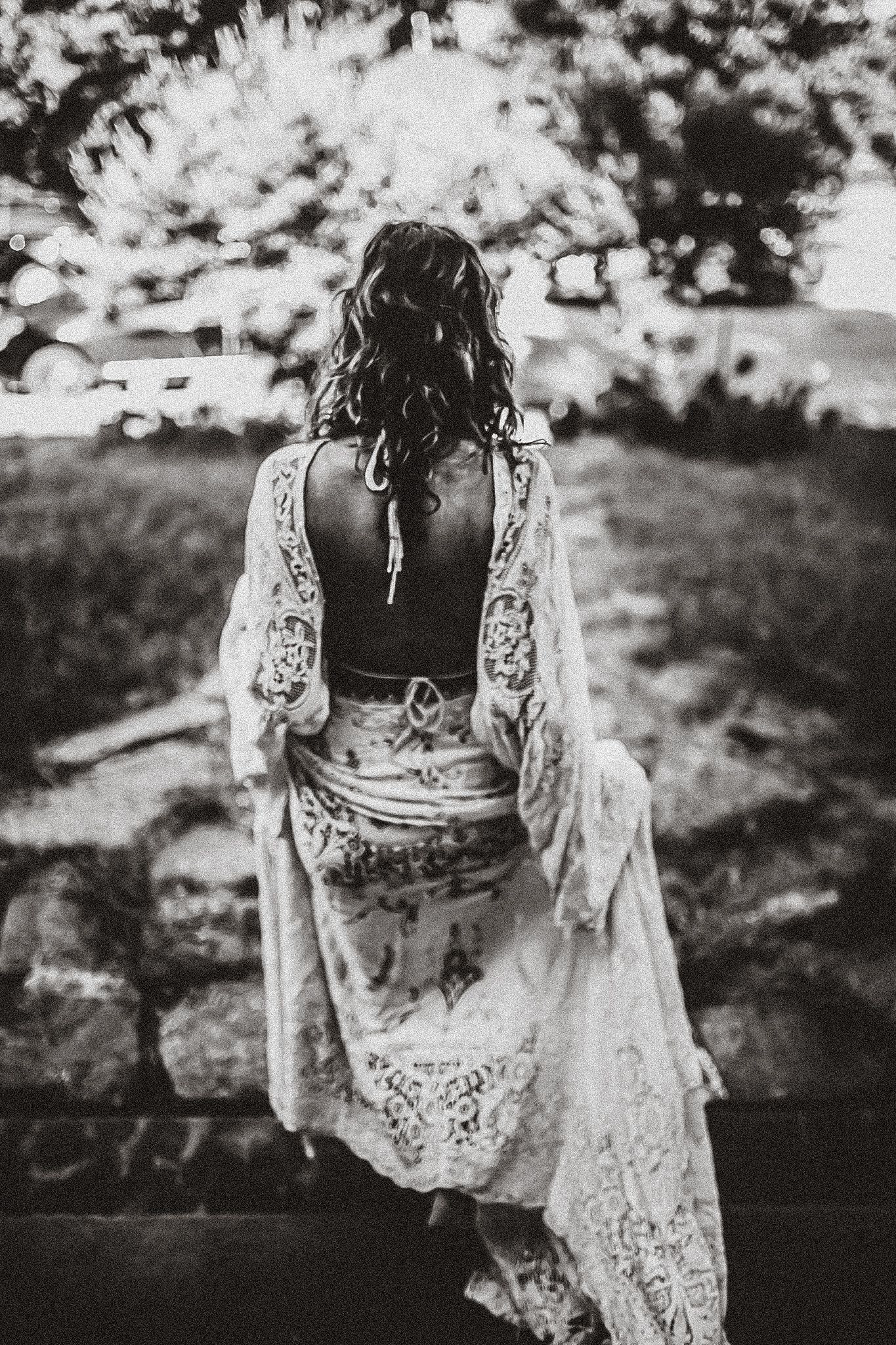 Back view of a lace dress with flowing sleeves photographed in black and white outdoors.