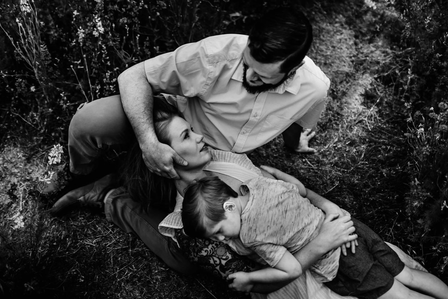 A romantic couple embraces in a natural outdoor setting during an engagement photo session.