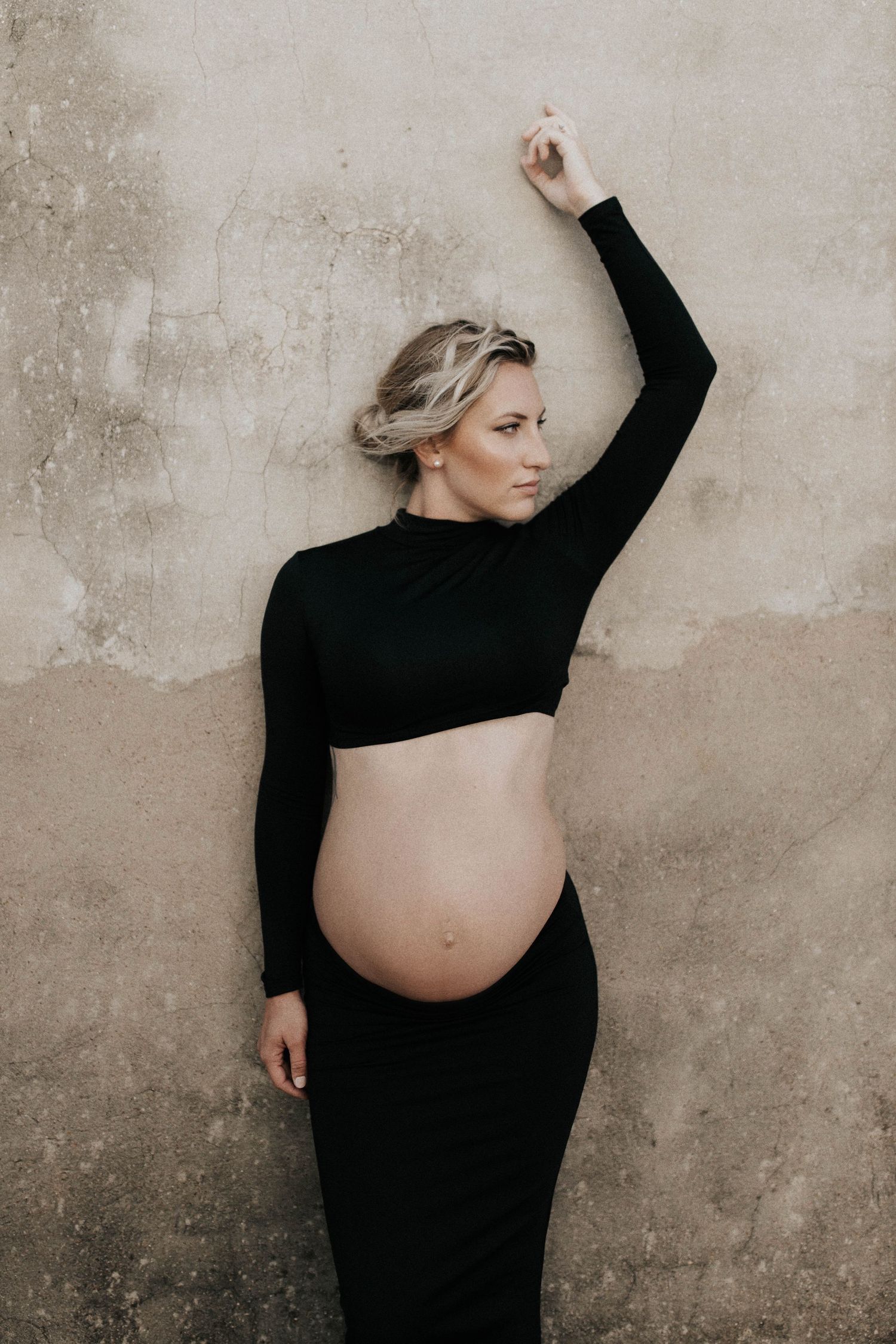 Artistic maternity photos showing silhouette against textured wall background.
