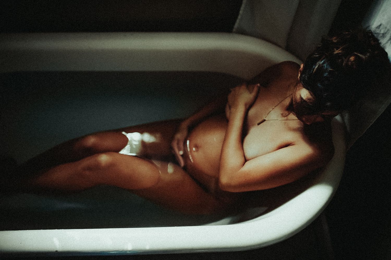 Artistic low-light photograph showing shadows and highlights in a bathtub setting.