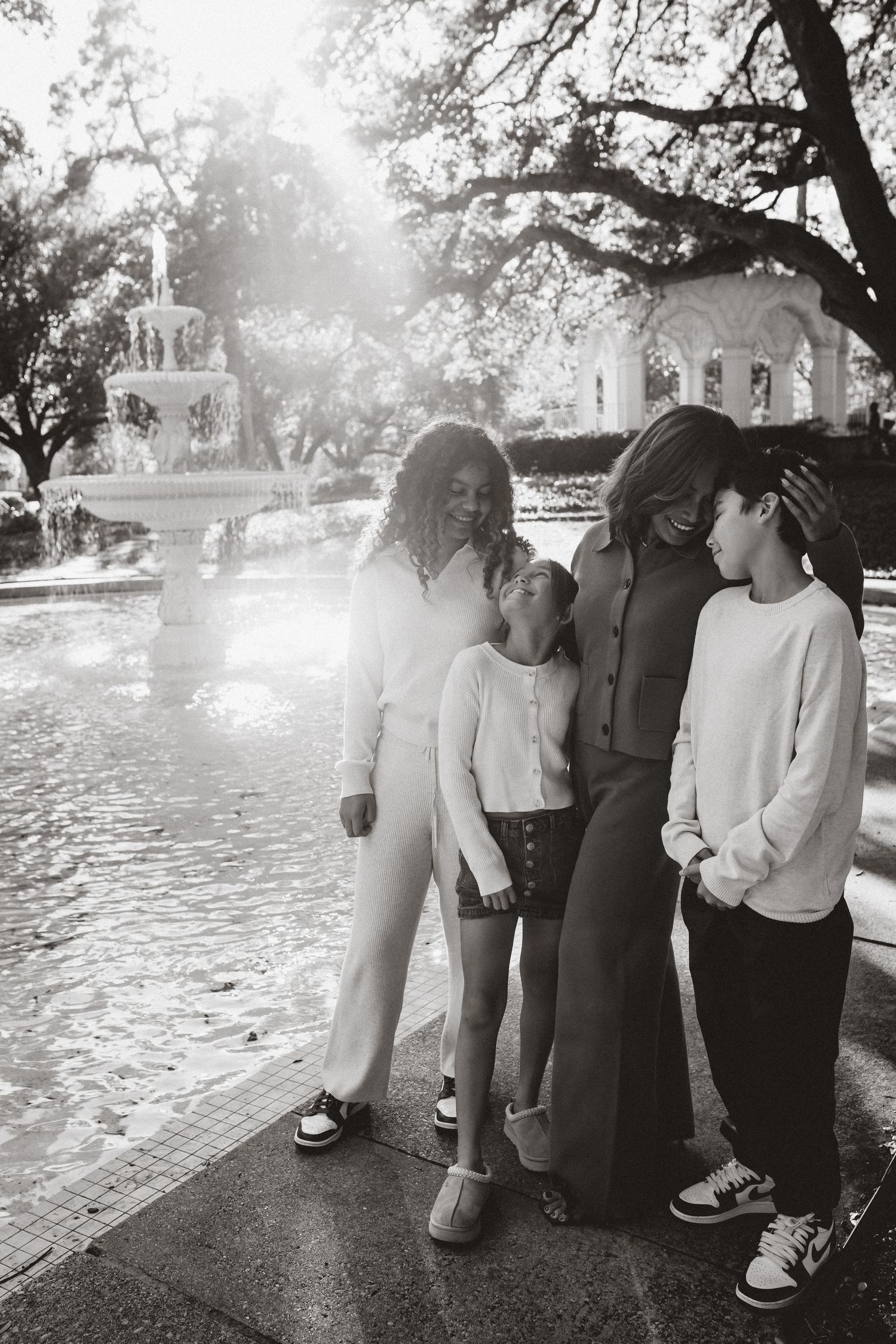 A group stands together on a path near a church on a bright misty day in black and white photography.