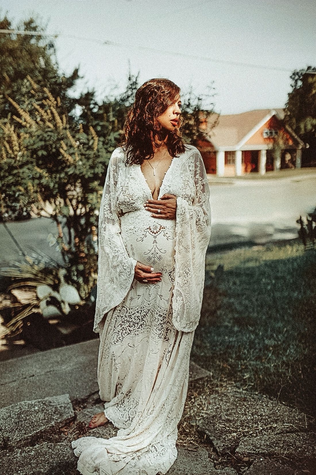 Ethereal outdoor portrait featuring a flowing white lace dress against a rural landscape.