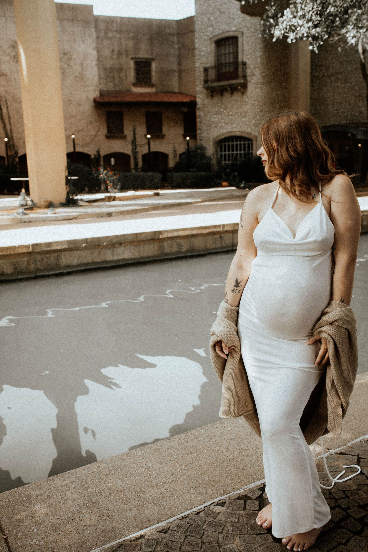 Person in white dress walking along urban pathway near historic building.