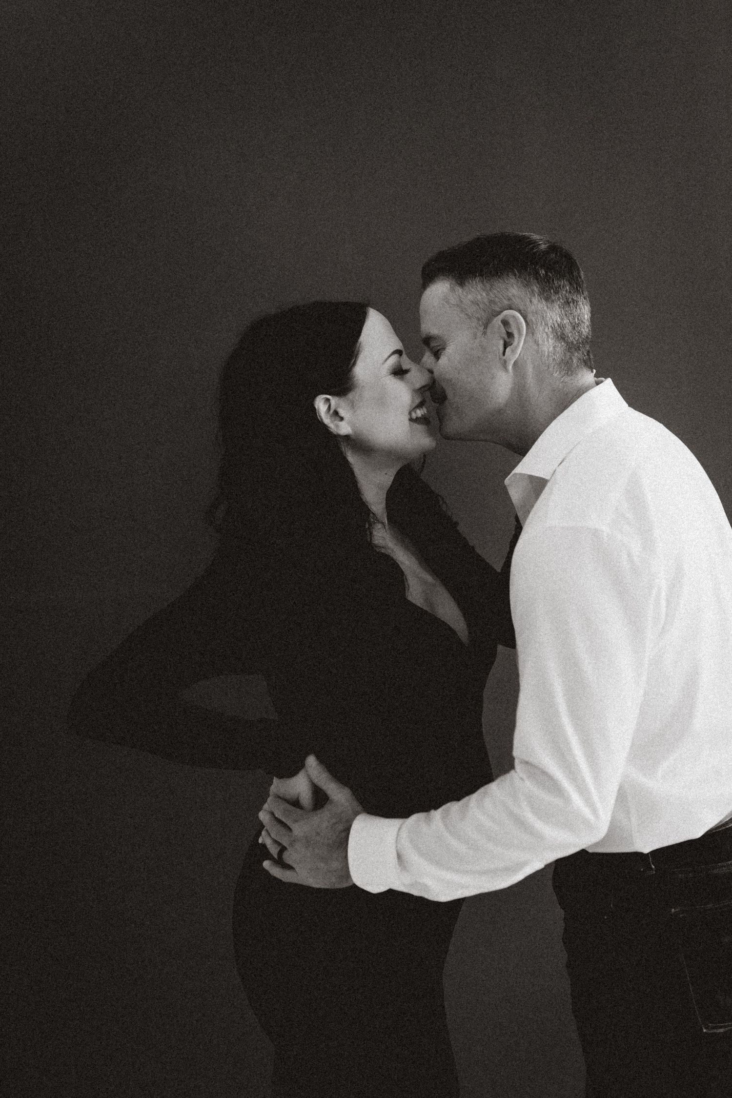 A romantic black and white photo series showing silhouettes of a couple embracing and kissing in the darkness.