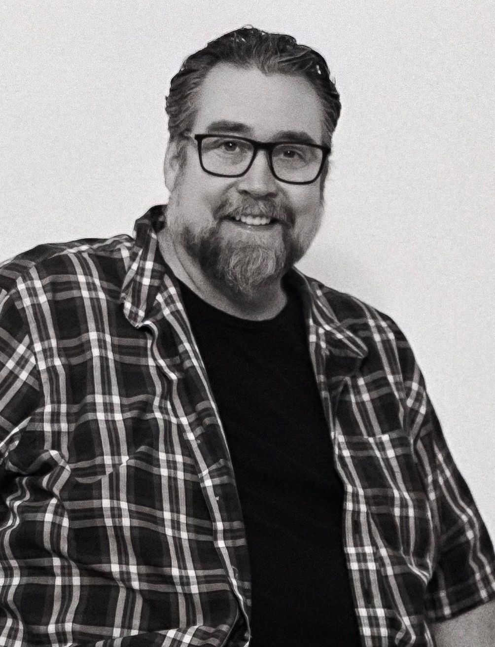 Man in plaid shirt and glasses shown in black and white headshot series.