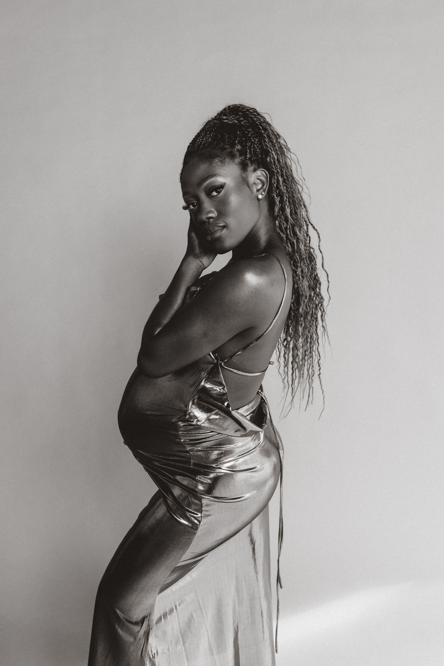 Black and white artistic photo series showing a model in a satin dress posing expressively against a plain backdrop.