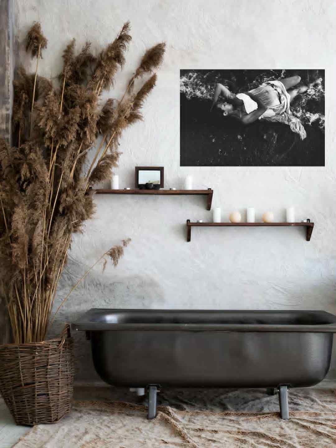 Modern bathroom interior with black bathtub, dried pampas grass, and black and white wall art.