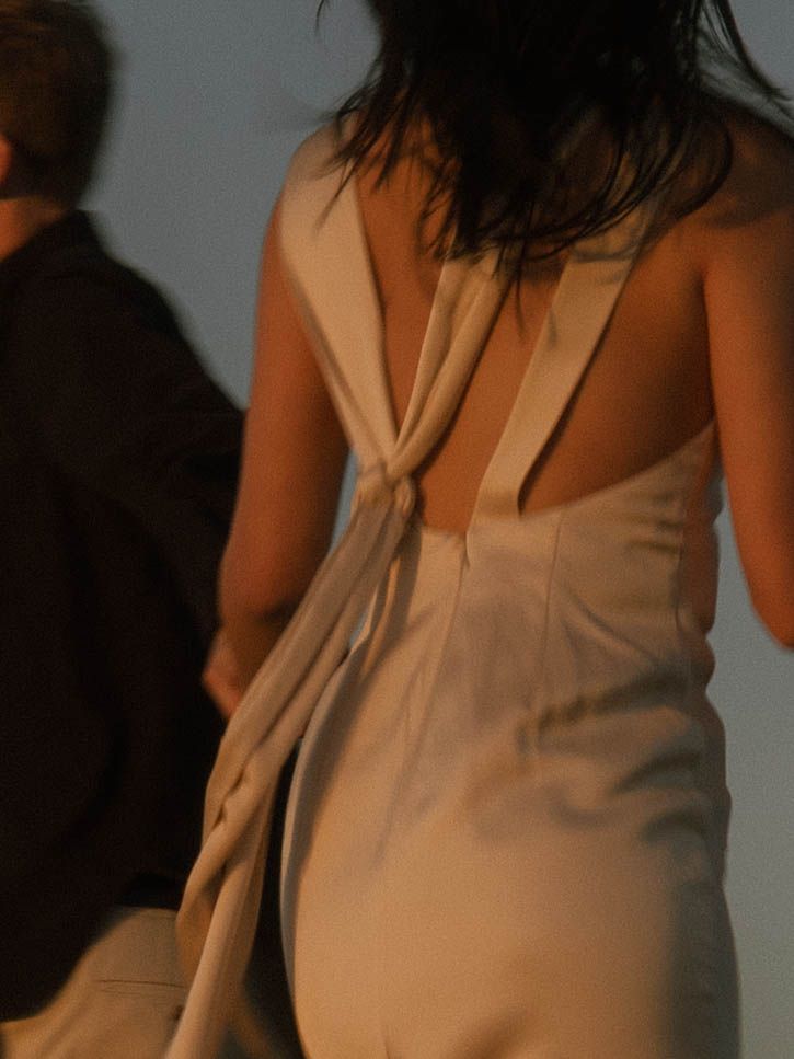 Close-up of an elegant cream-colored dress with draped back detail.
