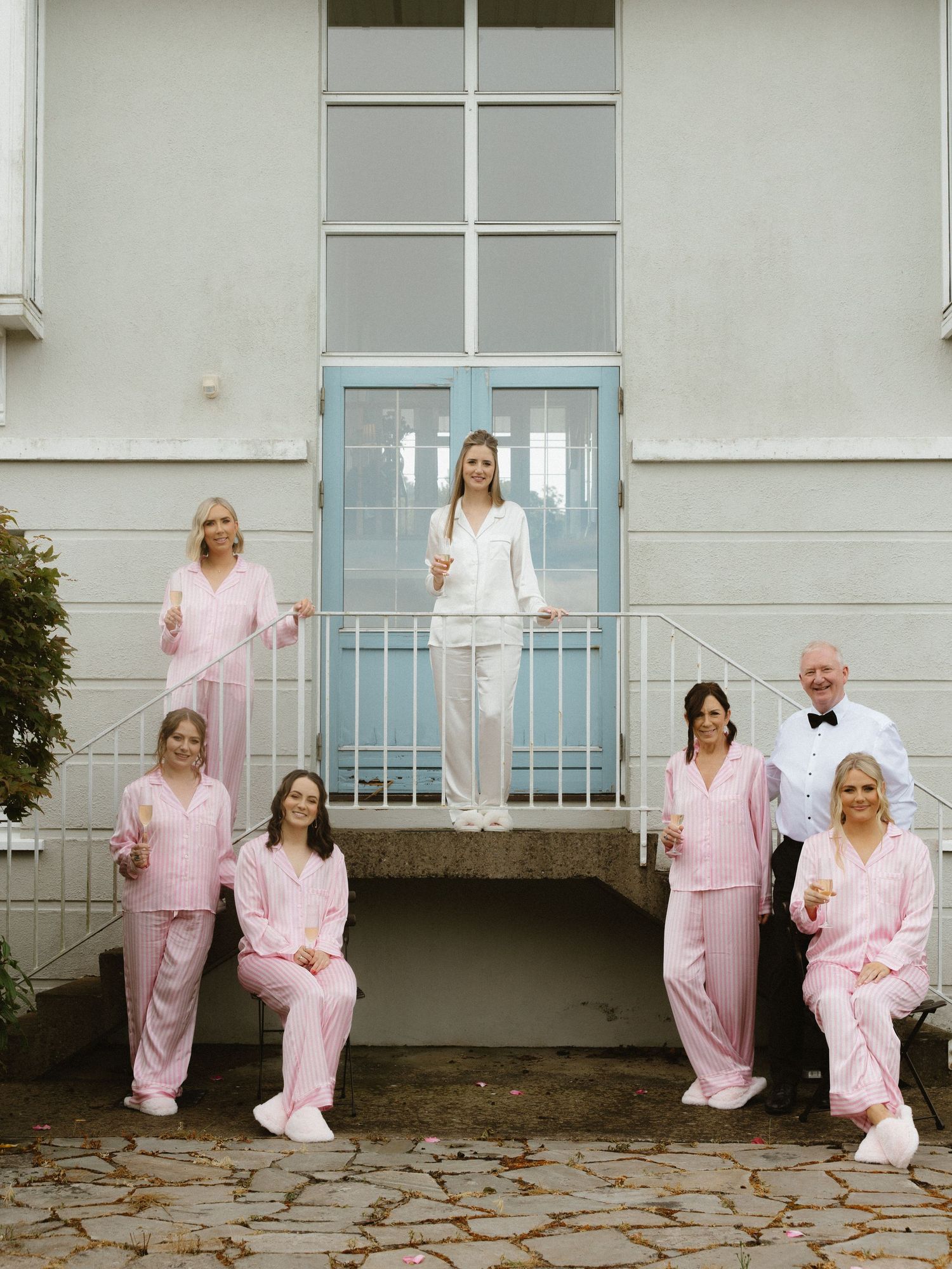 A sequence of five photos showing people in matching pink pajamas posing playfully on a white porch railing.