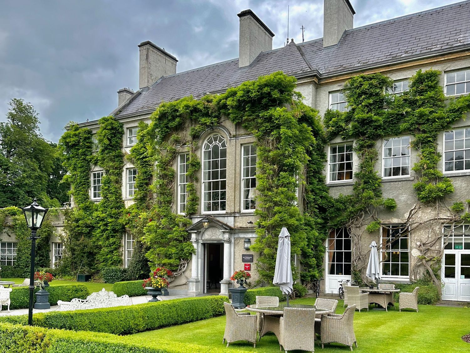 Elegant historic manor house with ivy-covered walls and manicured gardens featuring multiple Georgian-style windows.