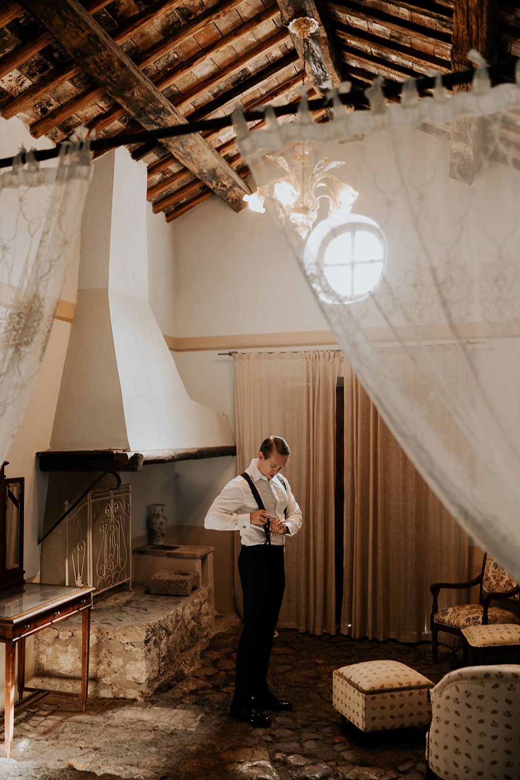 Moody wedding preparation scene with flowing white curtains and exposed wooden beams.