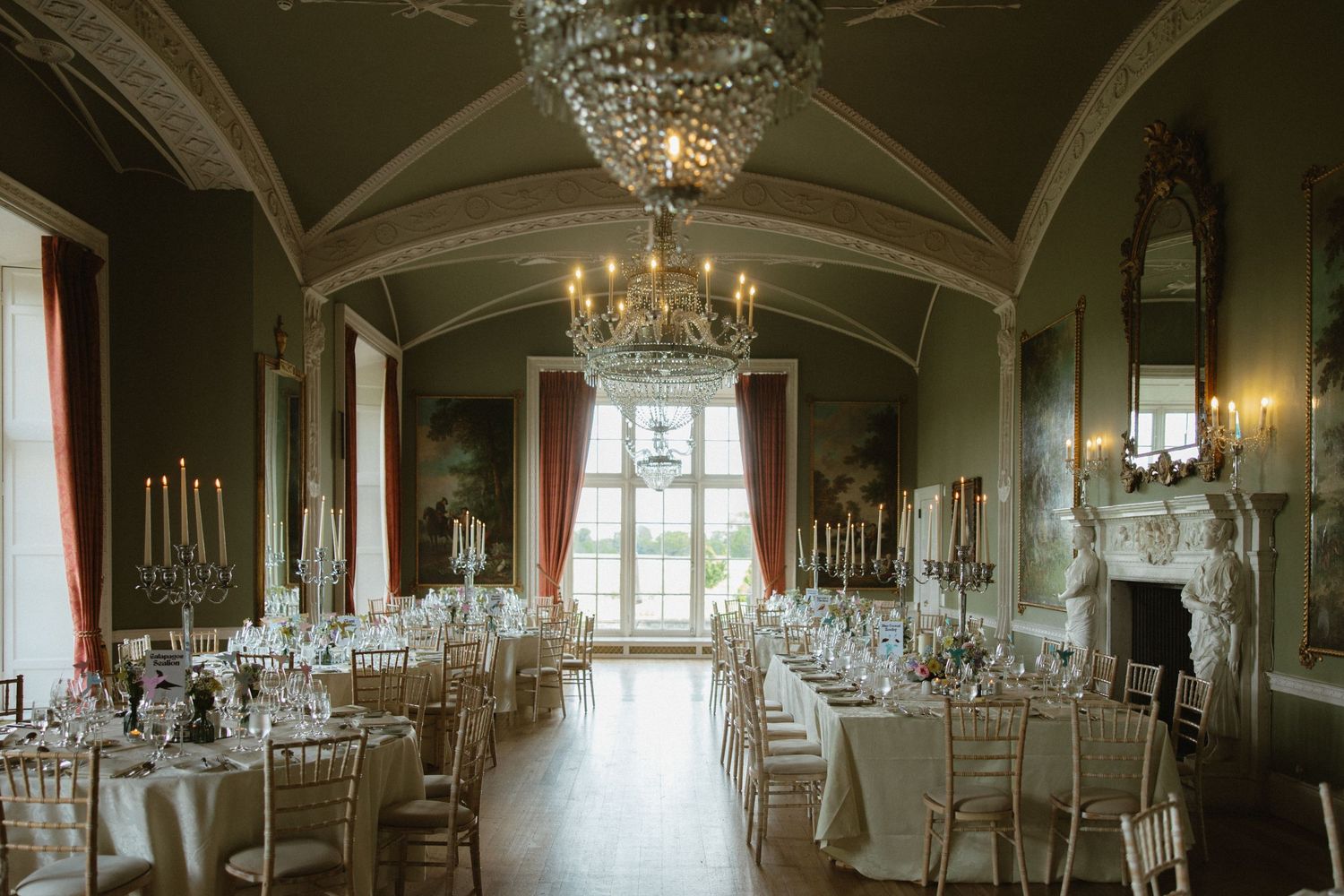 A grand ballroom set for a wedding reception with chandeliers and arched ceilings.