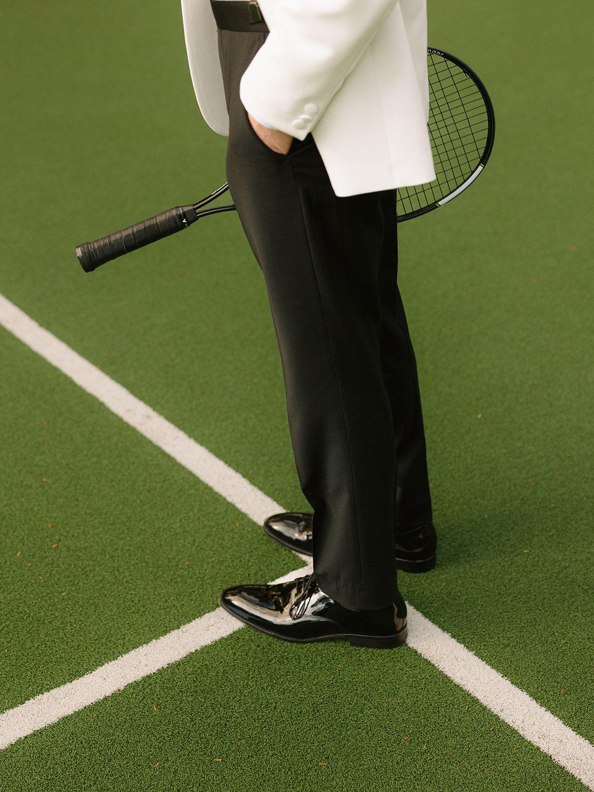 A tennis racket and formal attire shown against a green tennis court surface.